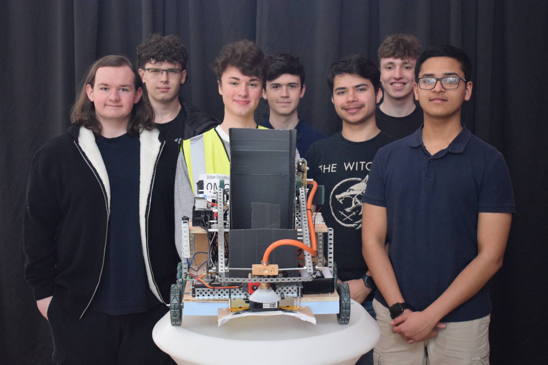 Boys standing in a line with their robot.