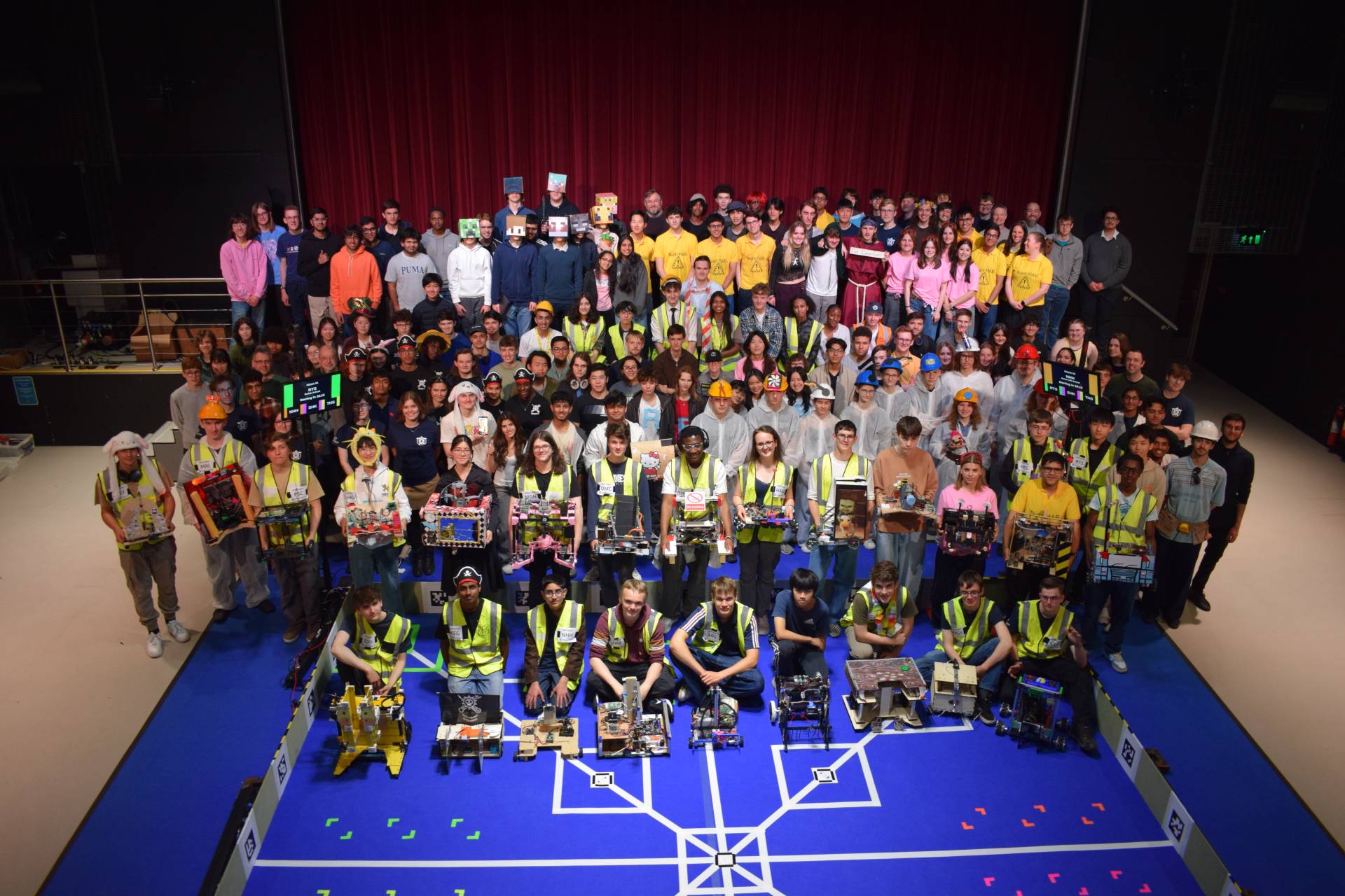 Hall with a group of students holding their robots