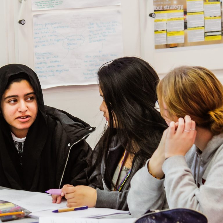 A group of students discussing a task in a Business class at Queen Mary's College.