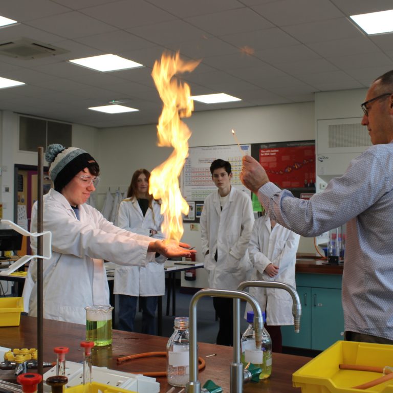 A QMC Science teacher and students showcasing an experiment in the specialist Science Labs at QMC