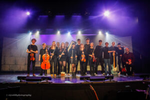 Music students who formed the Orchestra for Beauty and the Beast Musical at Queen Mary's College pictured on stage