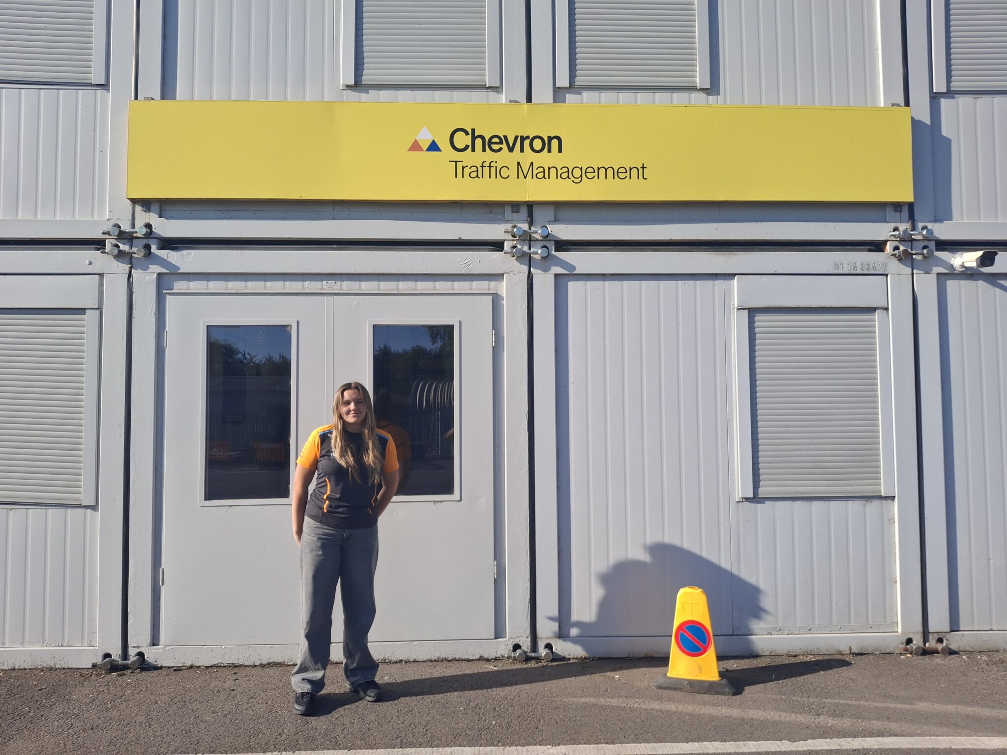 A person standing in front of a building with a yellow sign
