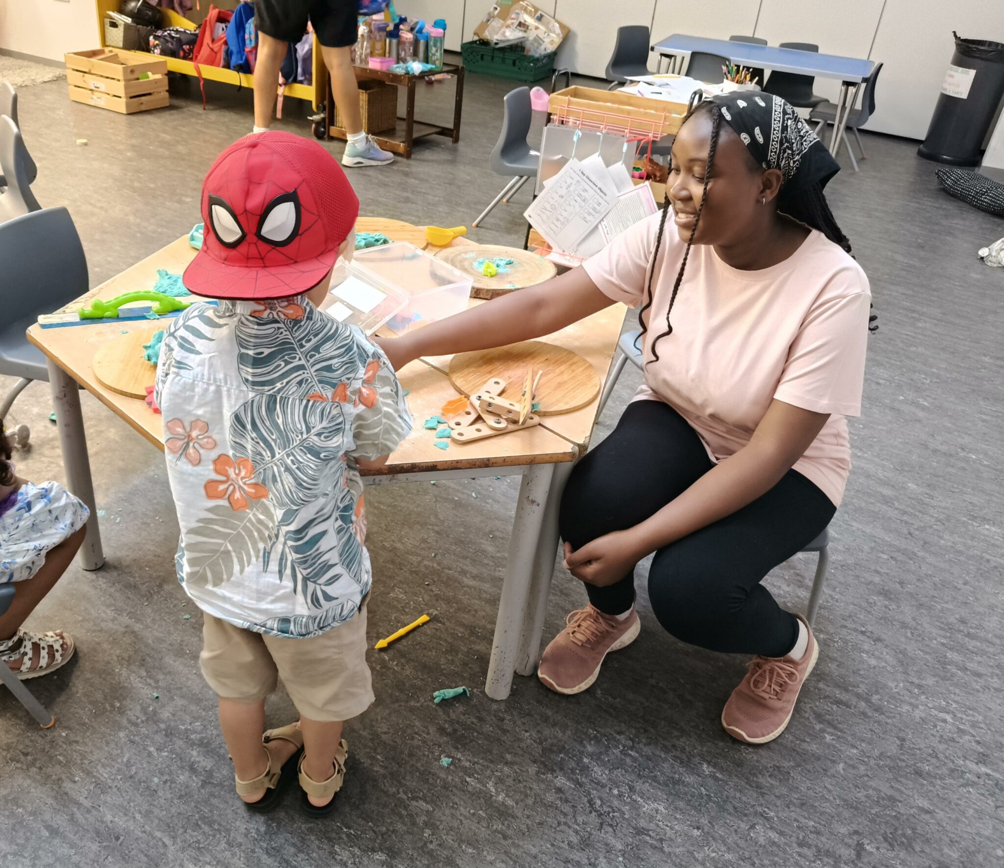 a person and a child sitting at a table in a classroom