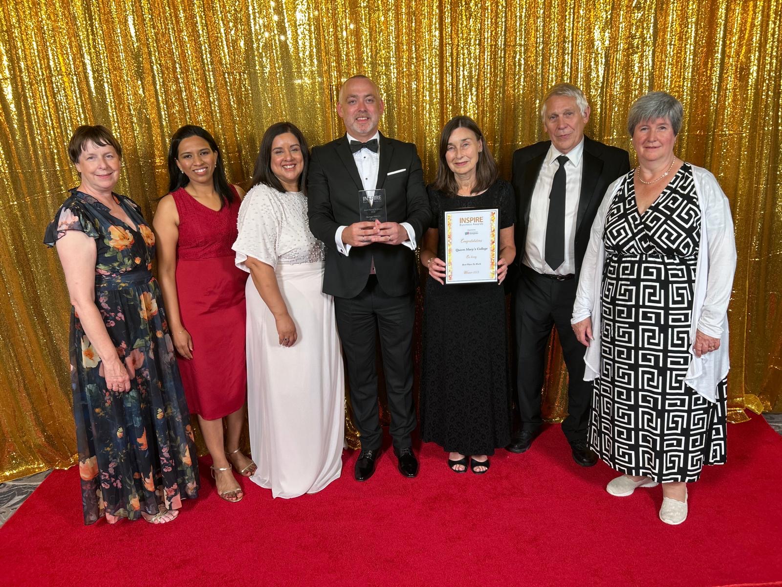 a group of people standing on a red carpet holding an award