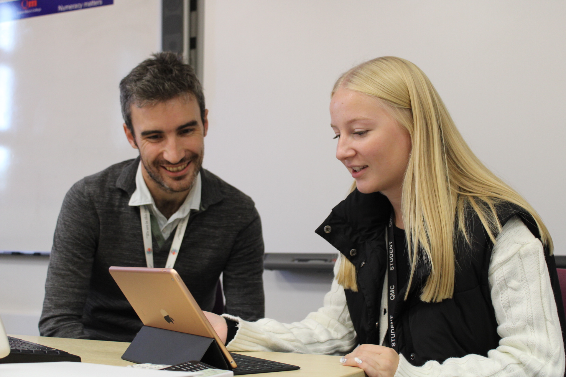 Two people sitting at a table looking at an ipad