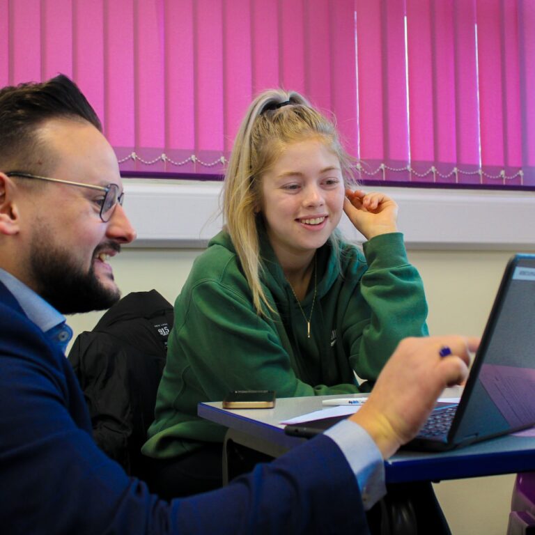 Two people sitting at a table with a laptop