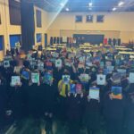 group of people standing in hall with pictures held up