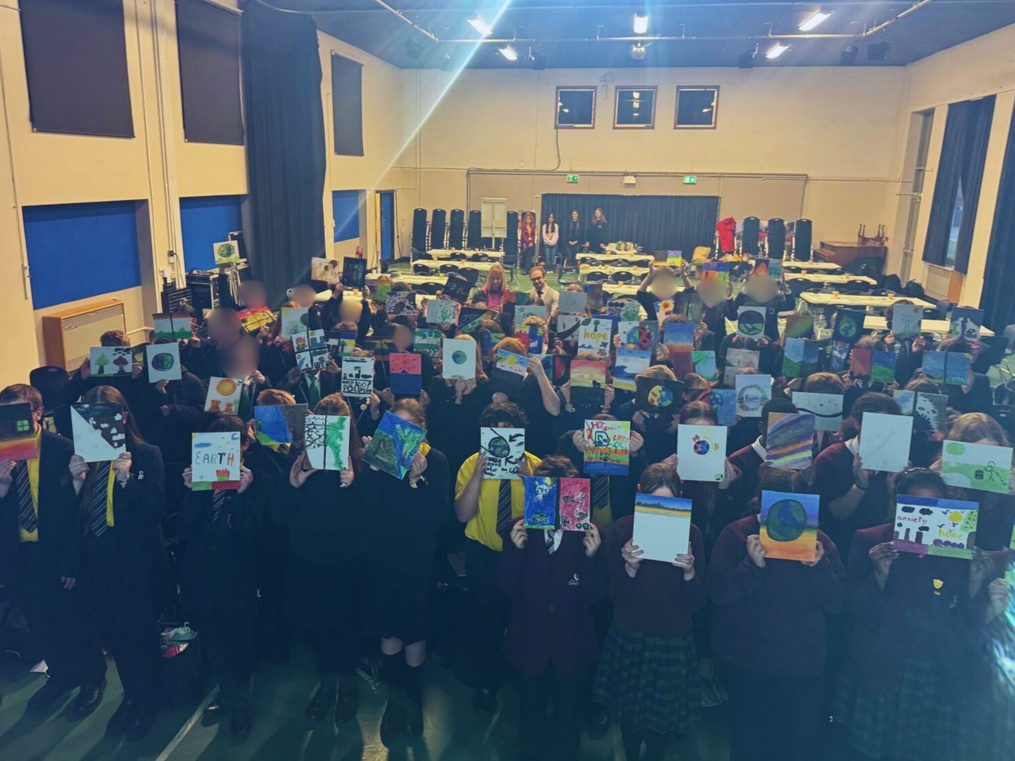 group of people standing in hall with pictures held up