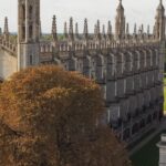 A wide aerial view of King's College Chapel and Cambridge University buildings under a bright sky.