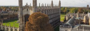 A wide aerial view of King's College Chapel and Cambridge University buildings under a bright sky.