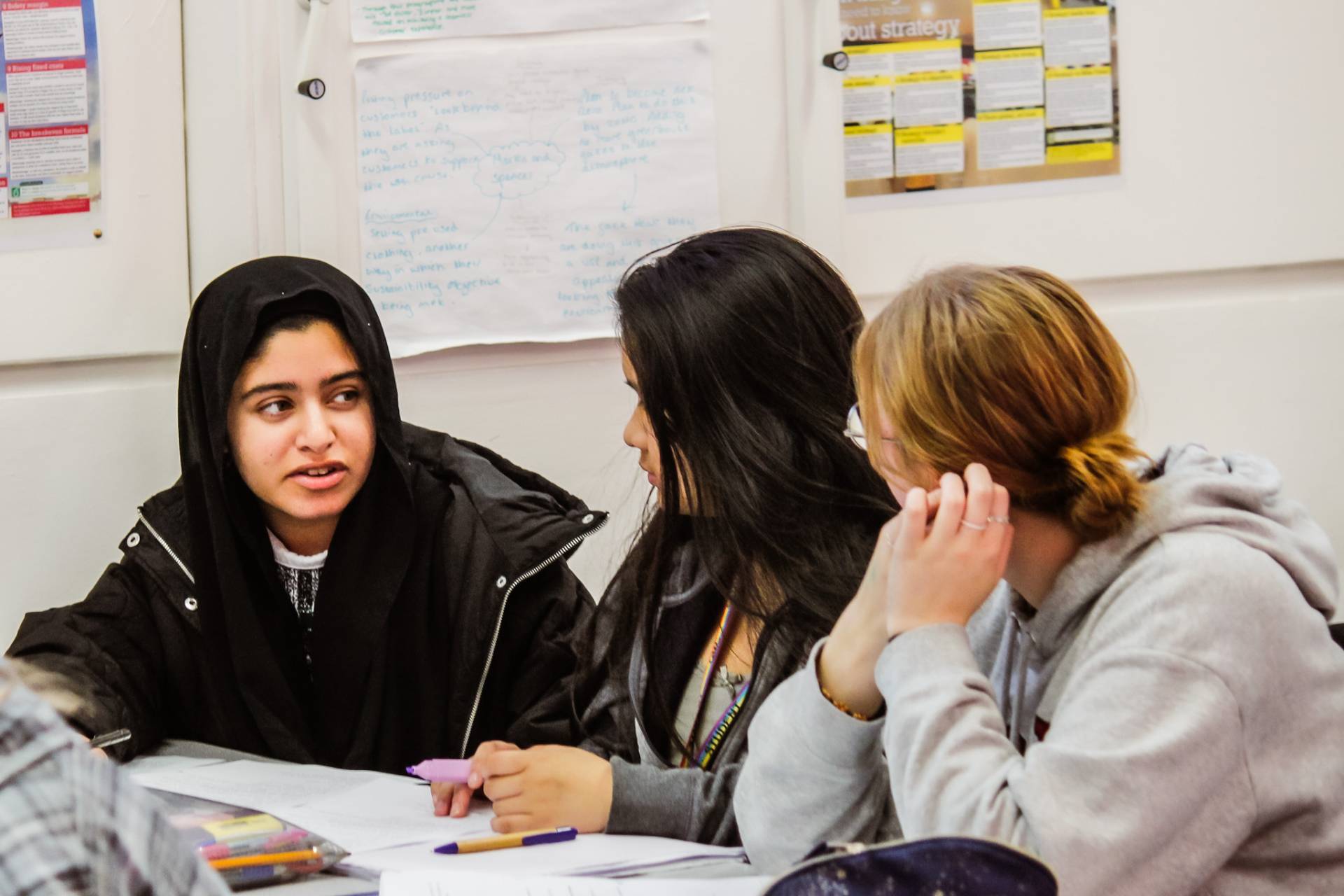 A group of students discussing a task in a Business class at Queen Mary's College.