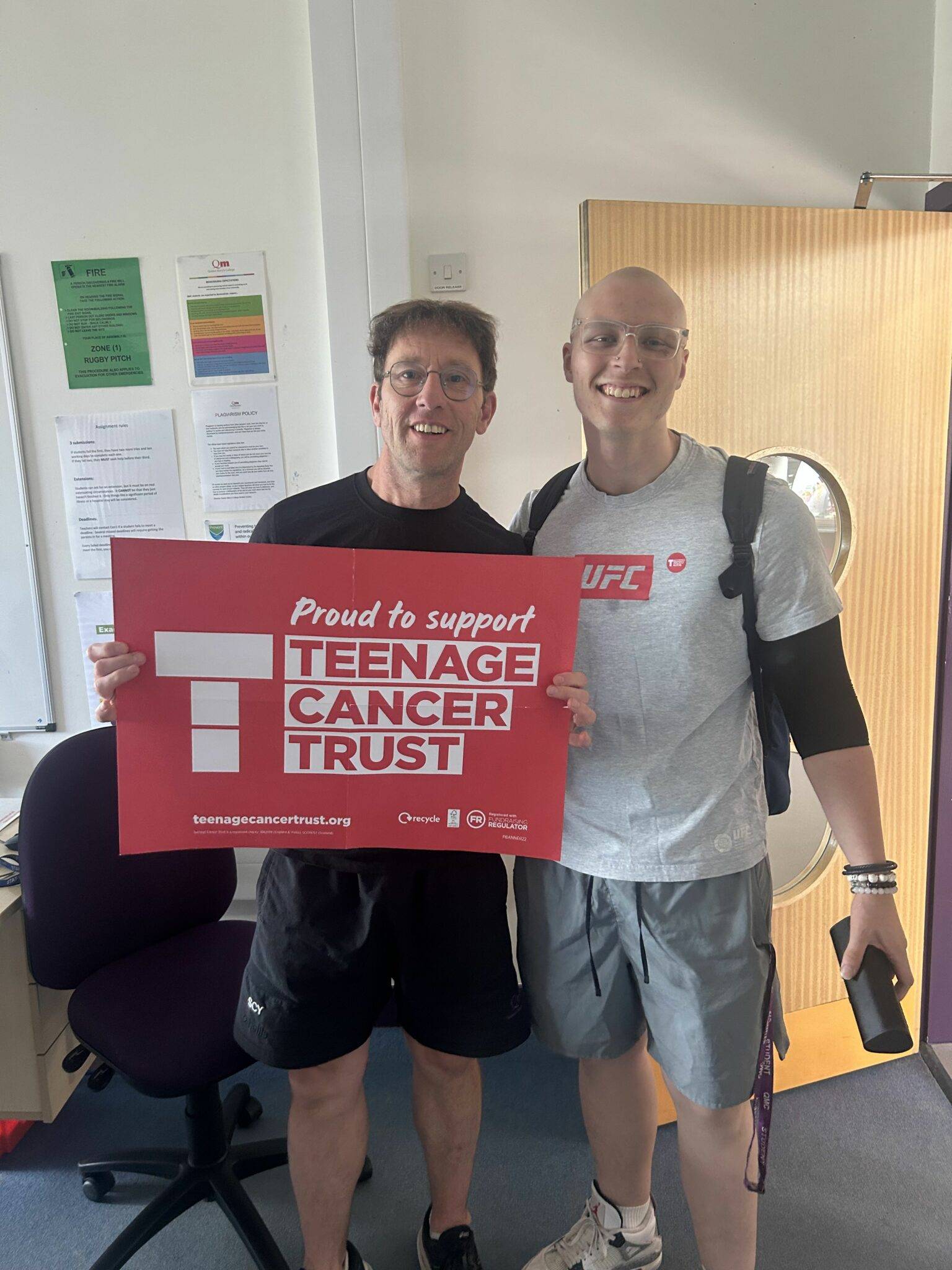 Two guys with one holding up a banner