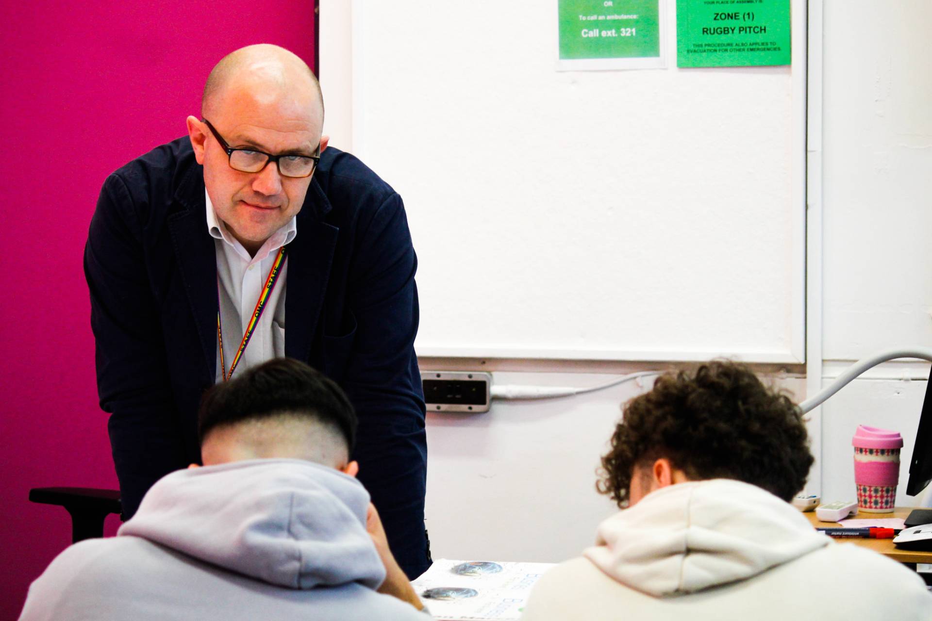 A teacher helping two students in a Business Class at Queen Mary's College.