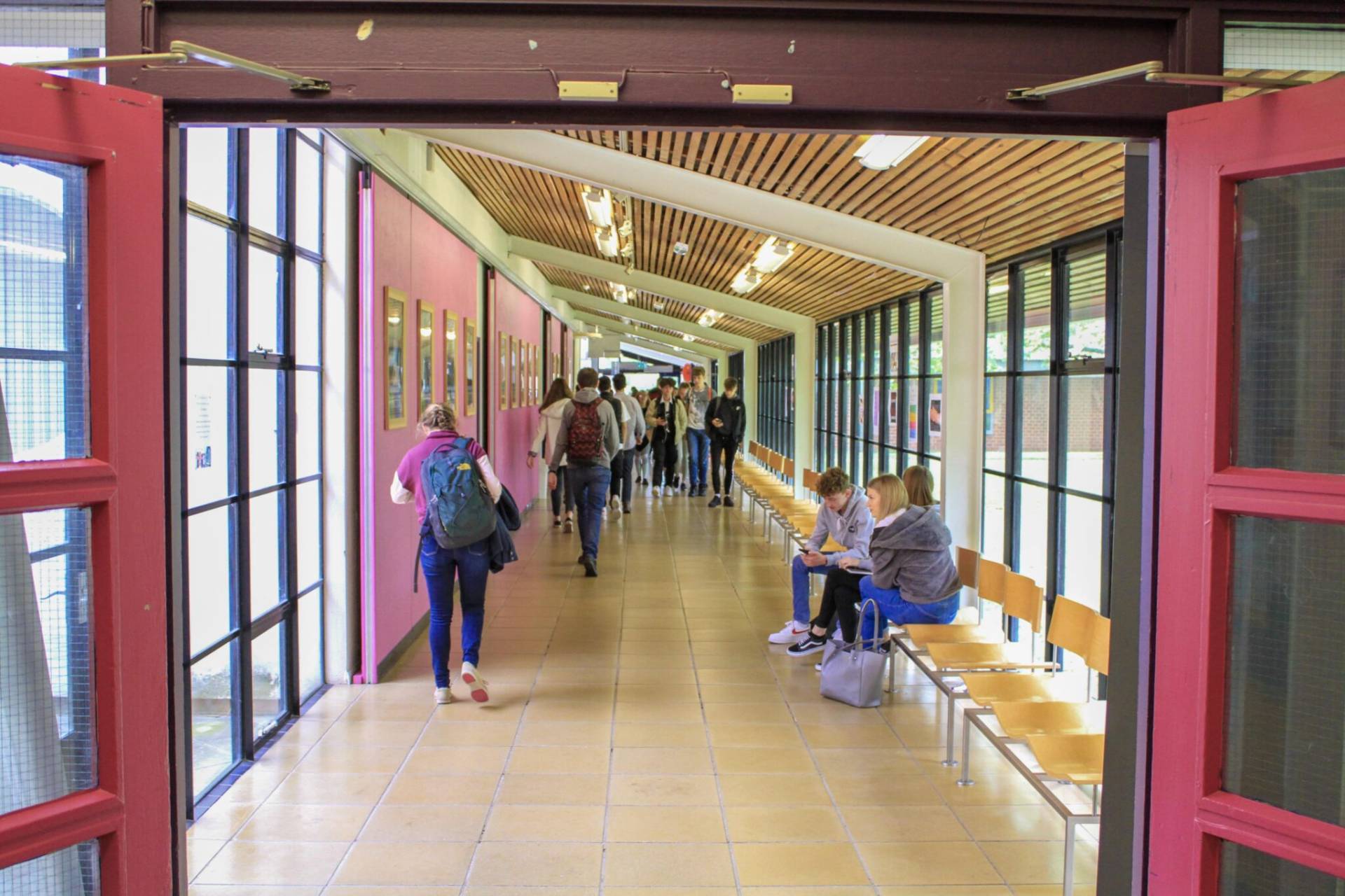 people walking through an open door in a school hallway