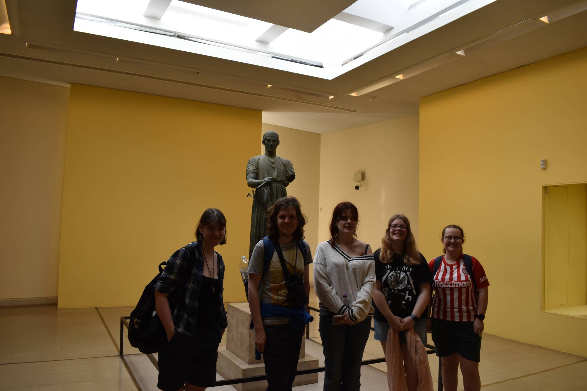 Students standing in front of a Greek statute