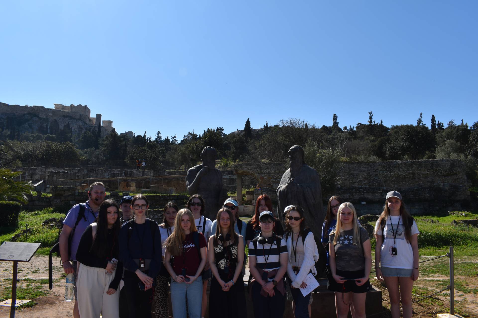 Students smiling in a group in front of a Greek statue